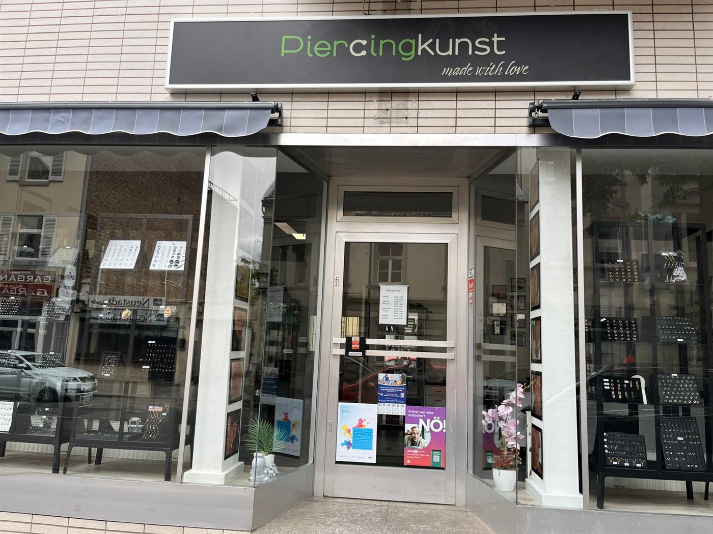 Ladenfront von Piercingkunst in der Kölner Straße mit grünem Schriftzug